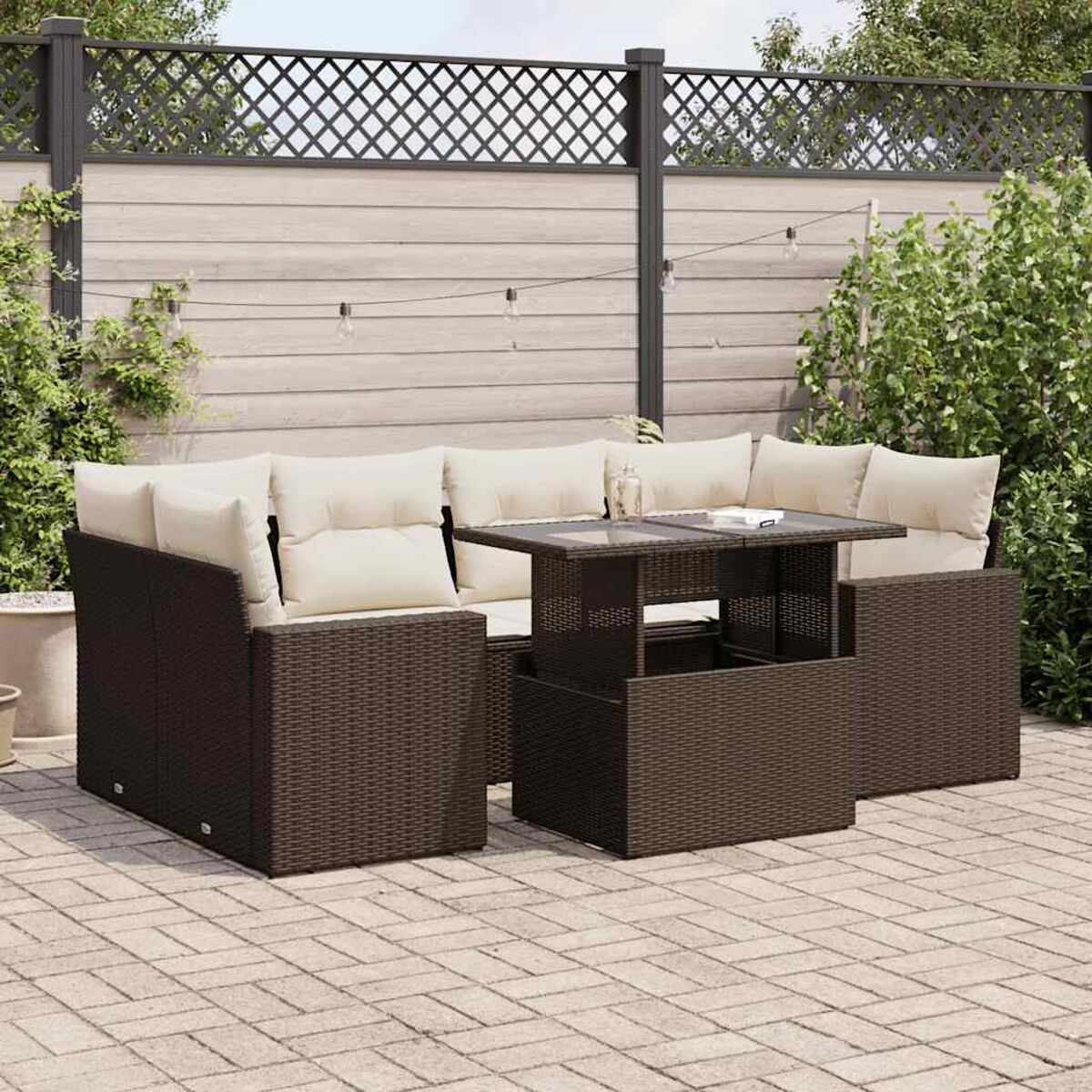 Sofá seccional de mimbre marrón con mesa elevable en un patio de ladrillos y luces.