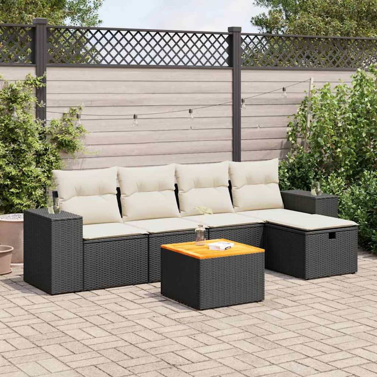 Un set in rattan per esterni, con un tavolo, divani e cuscini, su un patio in mattoni.