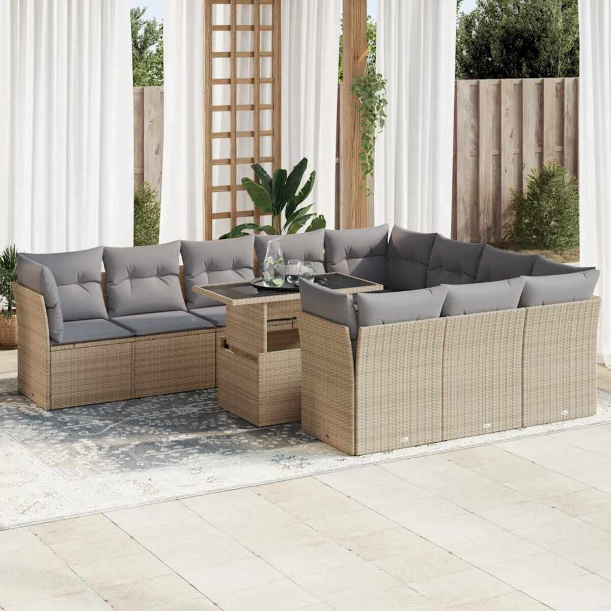 Divano componibile in rattan da esterno con cuscini grigi e tavolo con piano elevabile. Ambiente esterno.