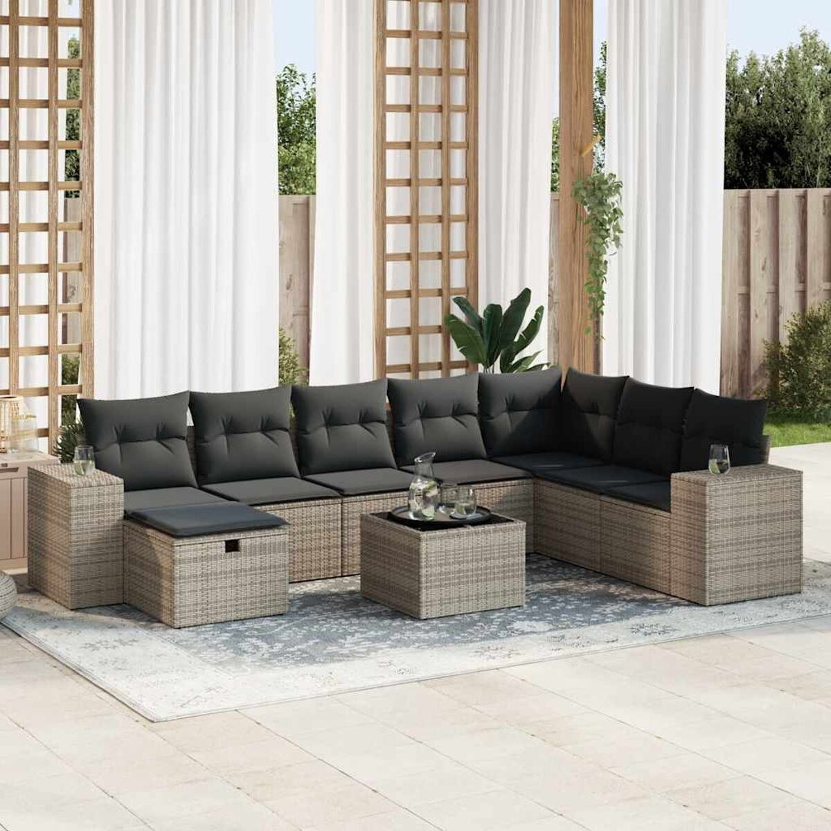 Outdoor-Ecksofa mit dunkelgrauen Kissen, einem kleinen Tisch und einem Teppich. Auf Terrasse mit Vorhängen.