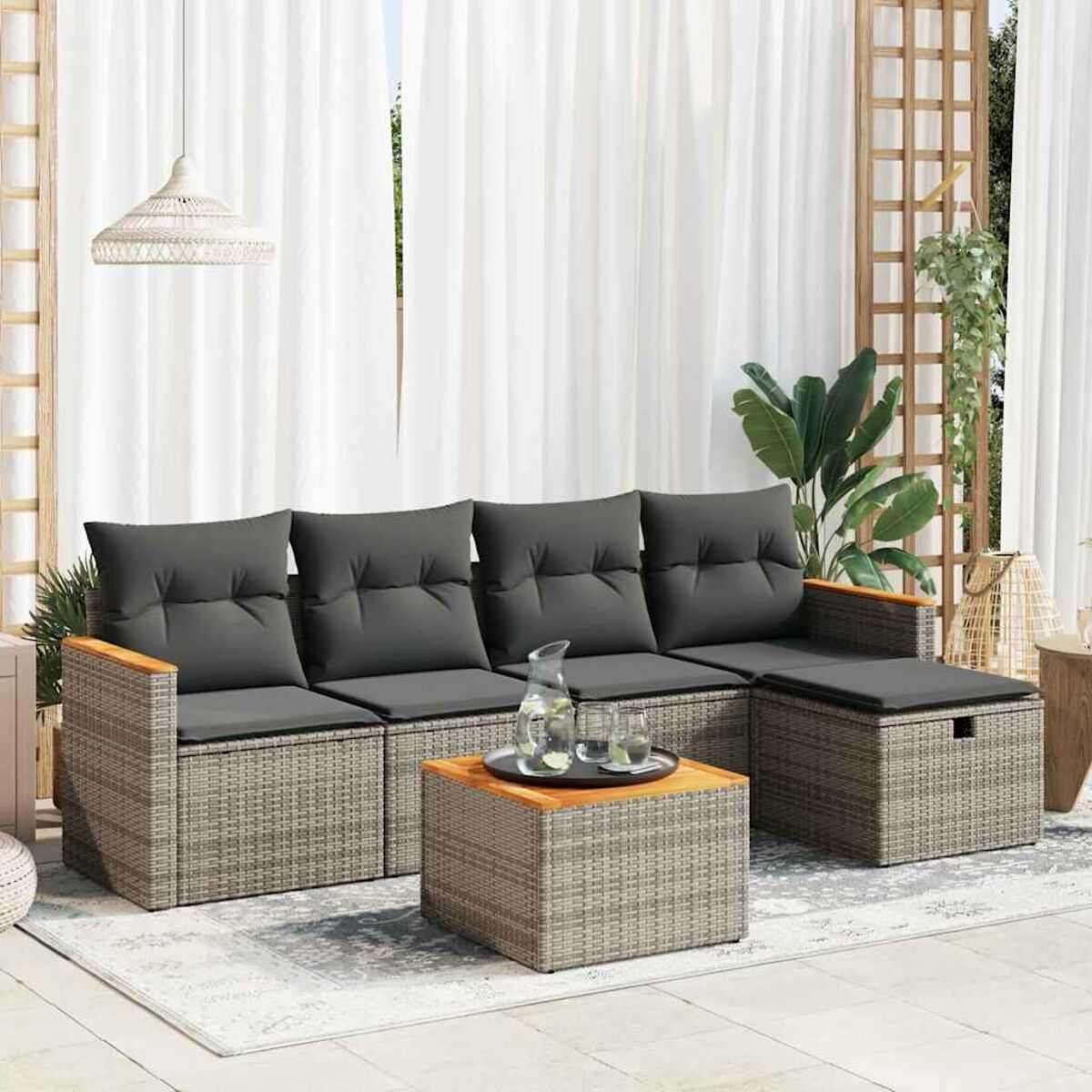 Set di divani da esterno con cuscini grigi, un tavolo in legno e un tappeto.