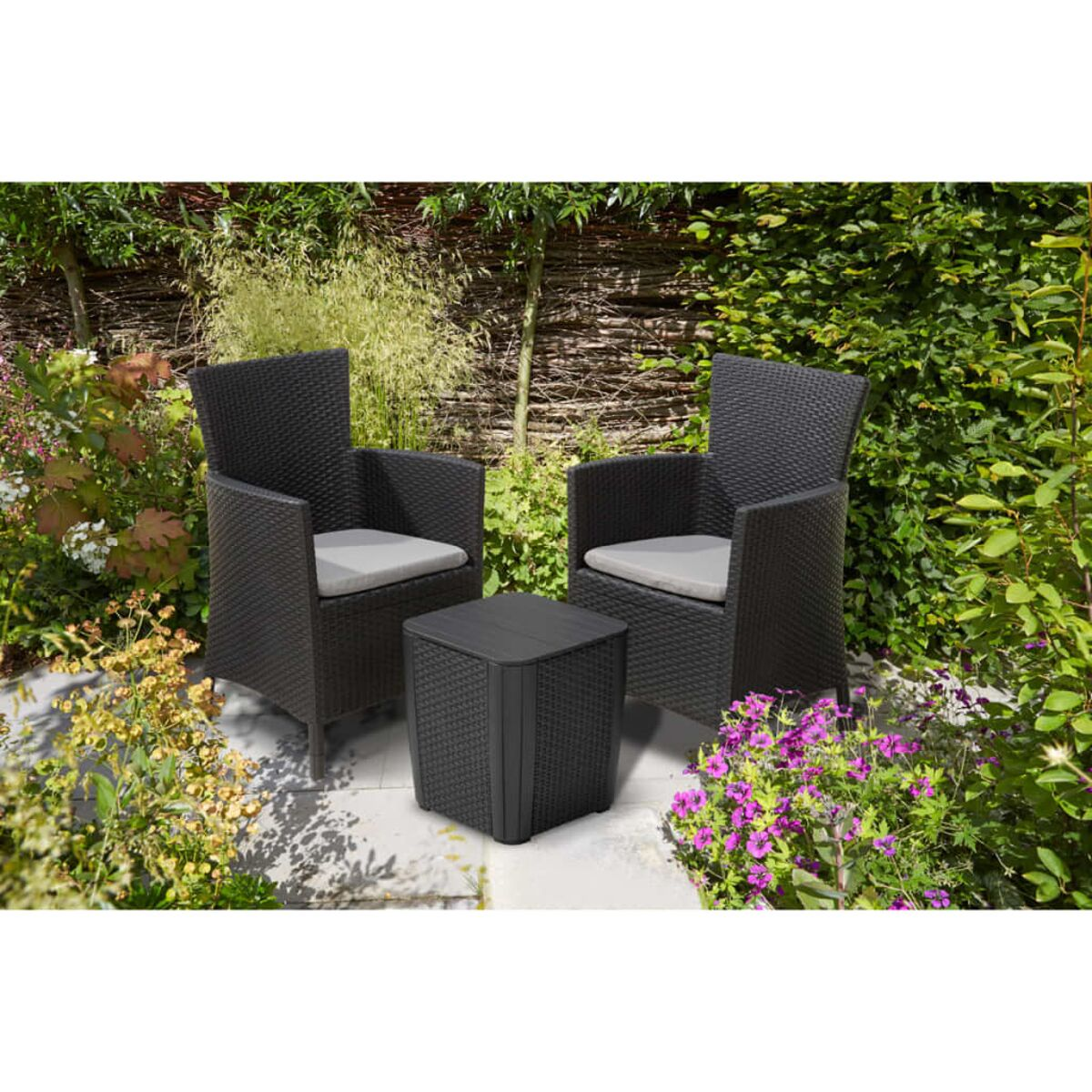 Zwei schwarze Rattan-Stühle mit grauen Kissen und ein kleiner quadratischer Tisch im Freien.