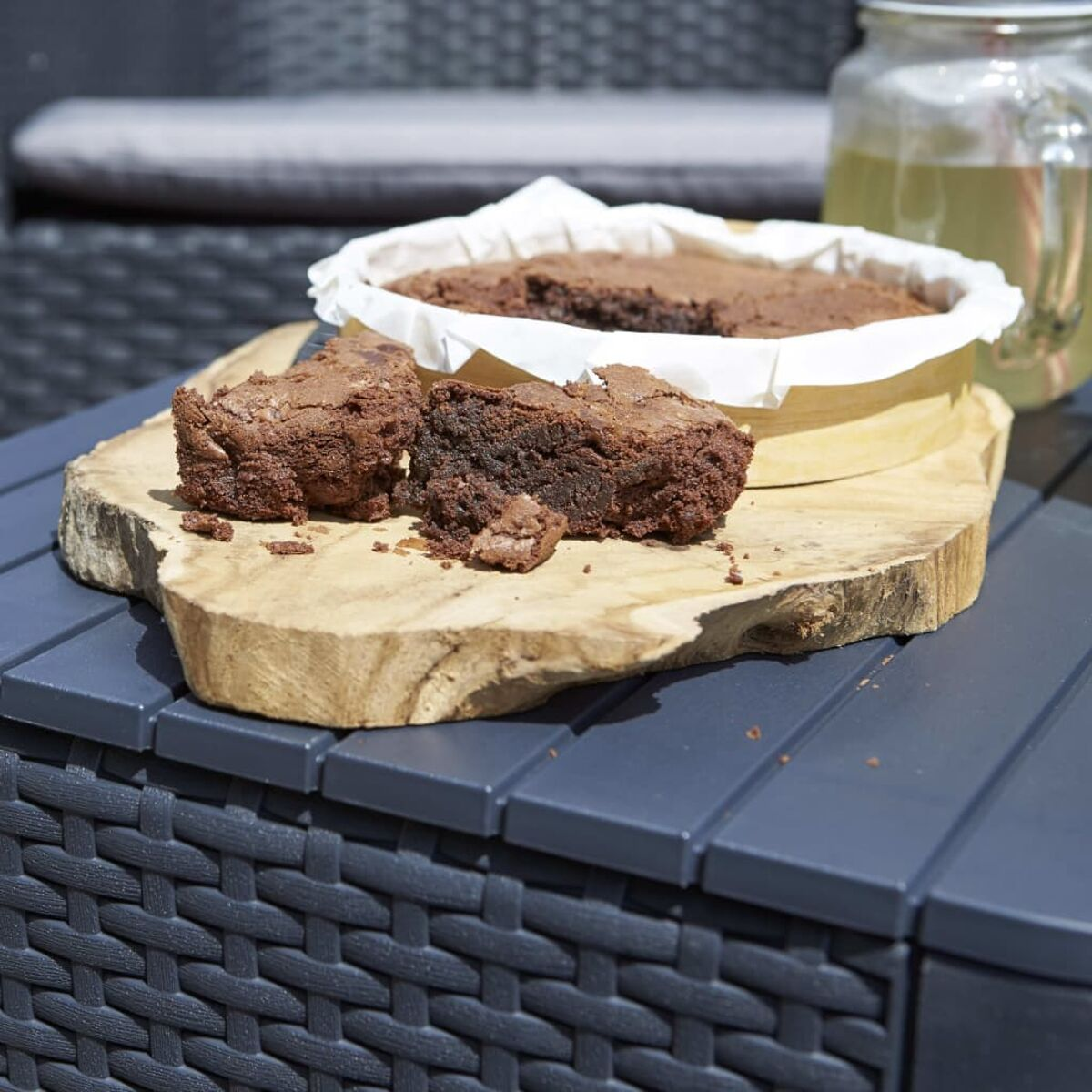 Brownies auf einem Holzbrett, mit einem Glas und einem grauen Tisch.