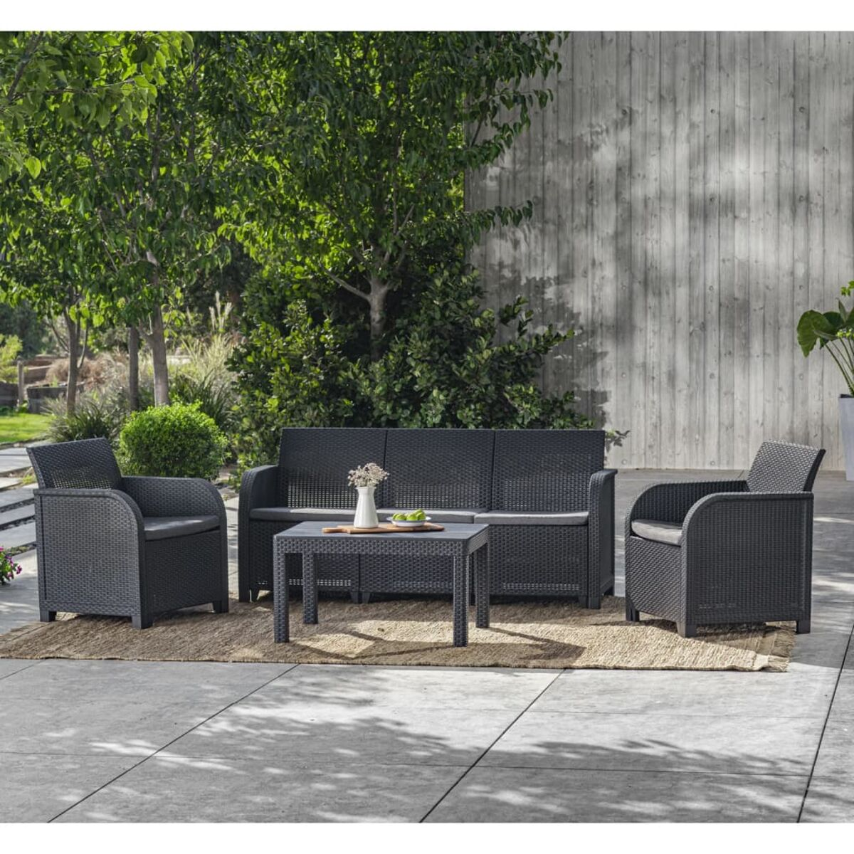 Schwarzes Gartenmöbel-Set auf einer Terrasse, einschließlich Sofa, Stühlen und Tisch.