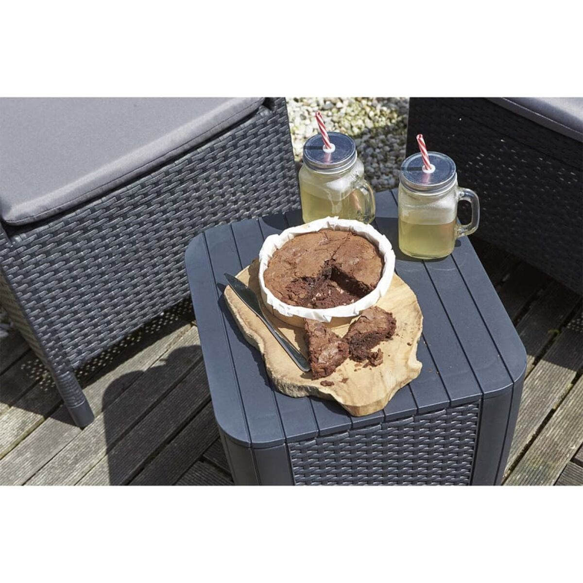 Tischdeko mit Kuchen, Getränken und Gläsern mit Strohhalmen. Draußen auf Holzterrasse.