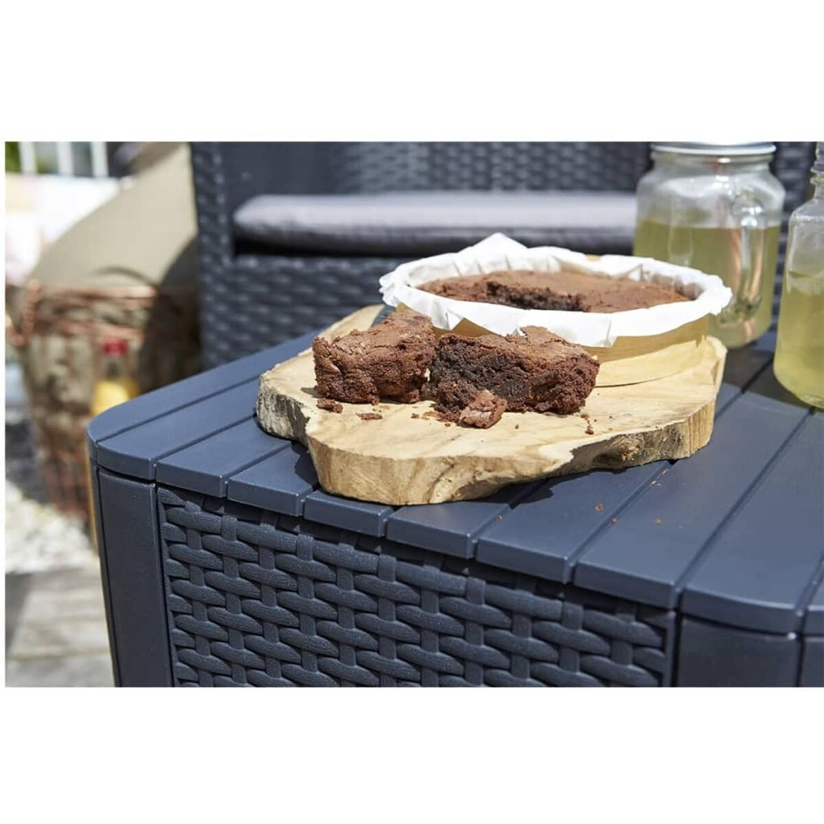 Brownies auf einem Holzbrett auf einem grauen Tisch. Gläser im Hintergrund.