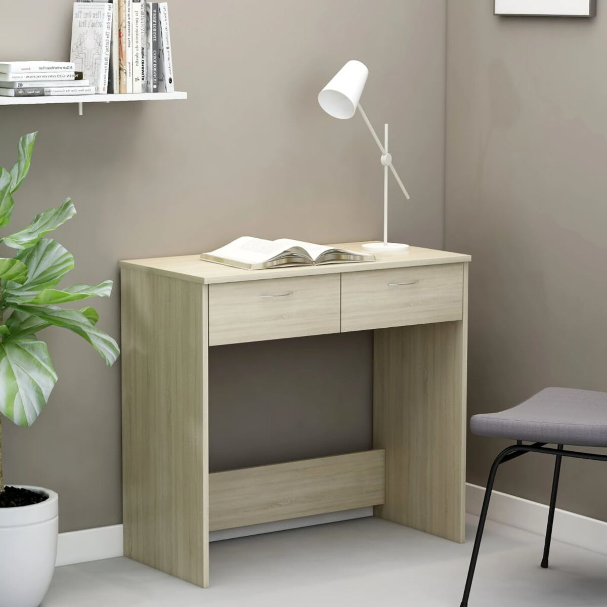 Ein helles Holzschreibtisch mit zwei Schubladen, einer Lampe und einem Buch.