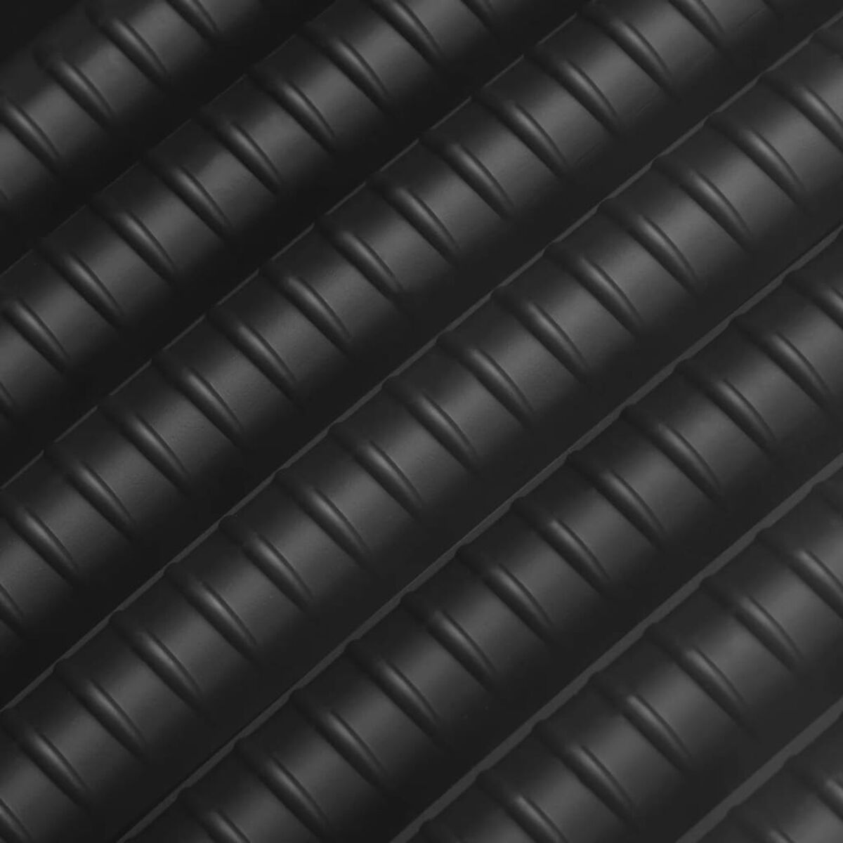 Nahaufnahme einer schwarzen, strukturierten Oberfläche mit diagonalen Rippen. Das Muster ist geriffelt.
