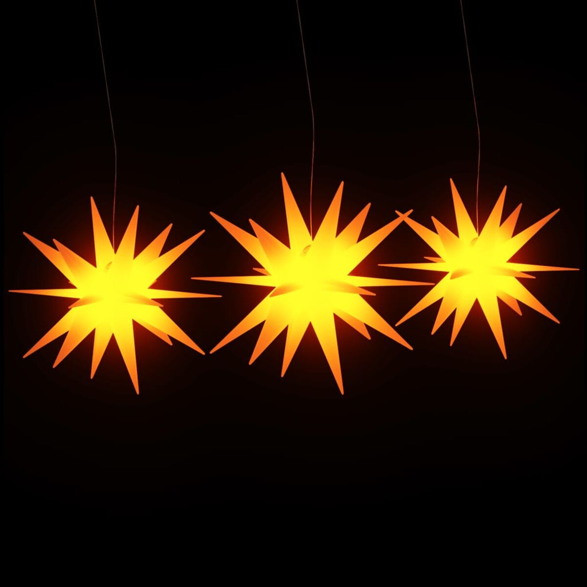 Drei orangefarbene sternförmige Lichter hängen vor schwarzem Hintergrund.