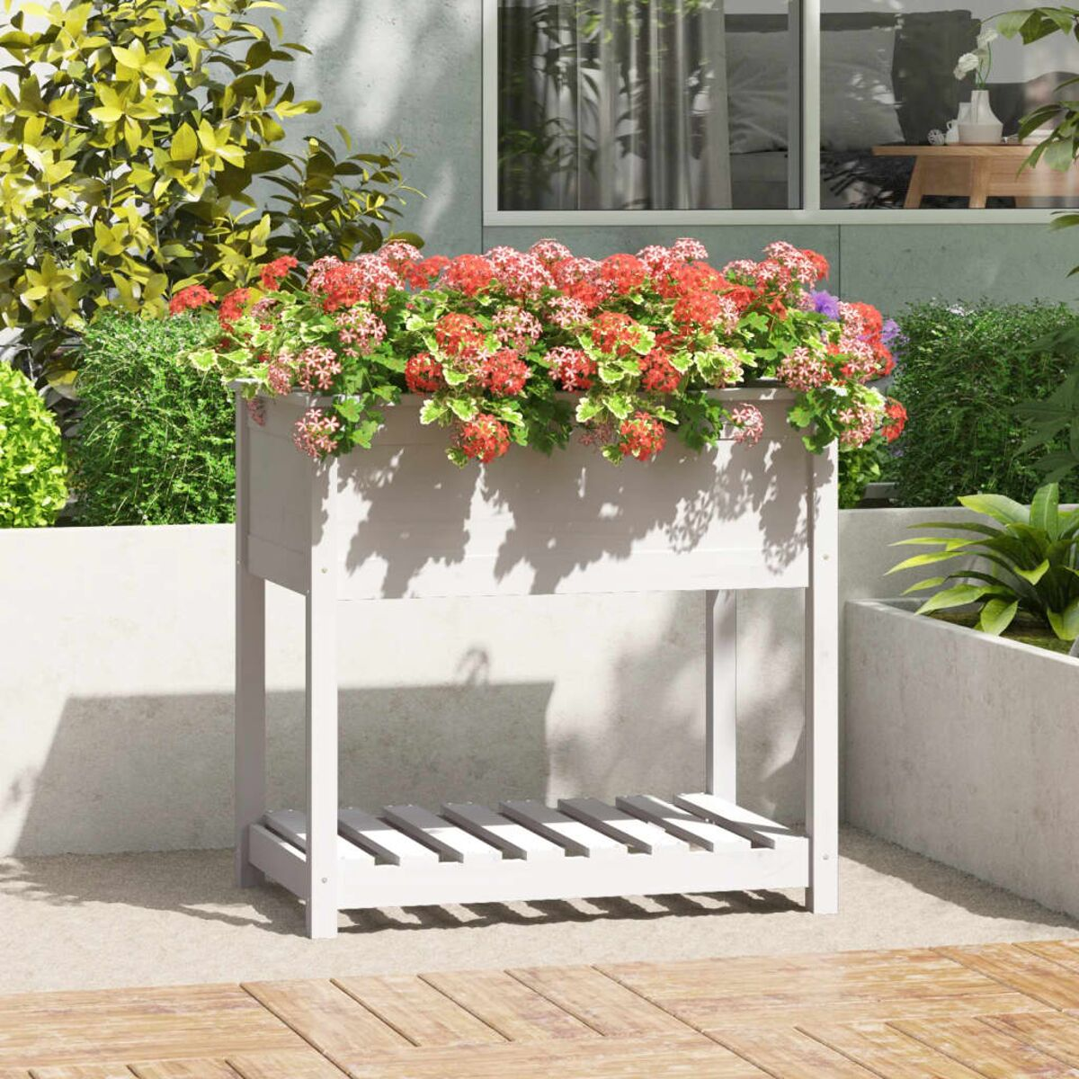Weißes Hochbeet mit roten Blumen, Holzterrasse, graue Betonmauer.