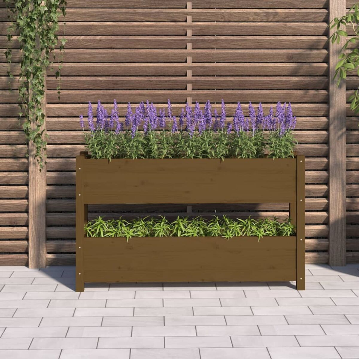 Holzpflanzer mit lila Blumen und grünen Pflanzen auf einer gefliesten Terrasse, Holzzaun im Hintergrund.