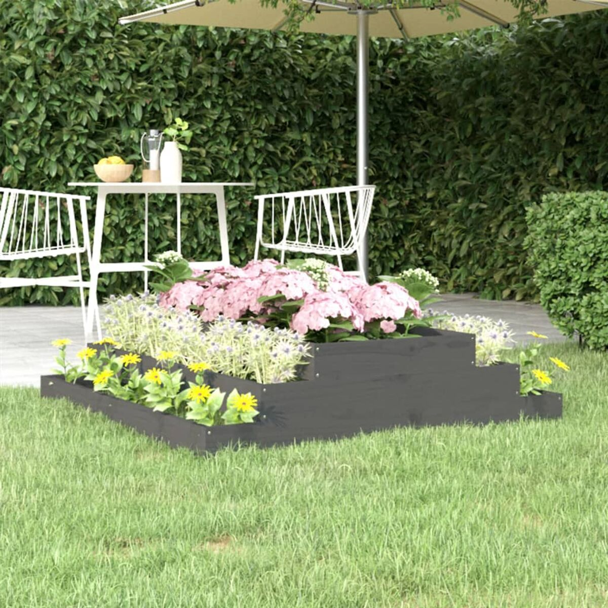 Ein mehrstufiges Blumenbeet mit rosa Blüten, umgeben von grünem Gras und einem weißen Tisch.