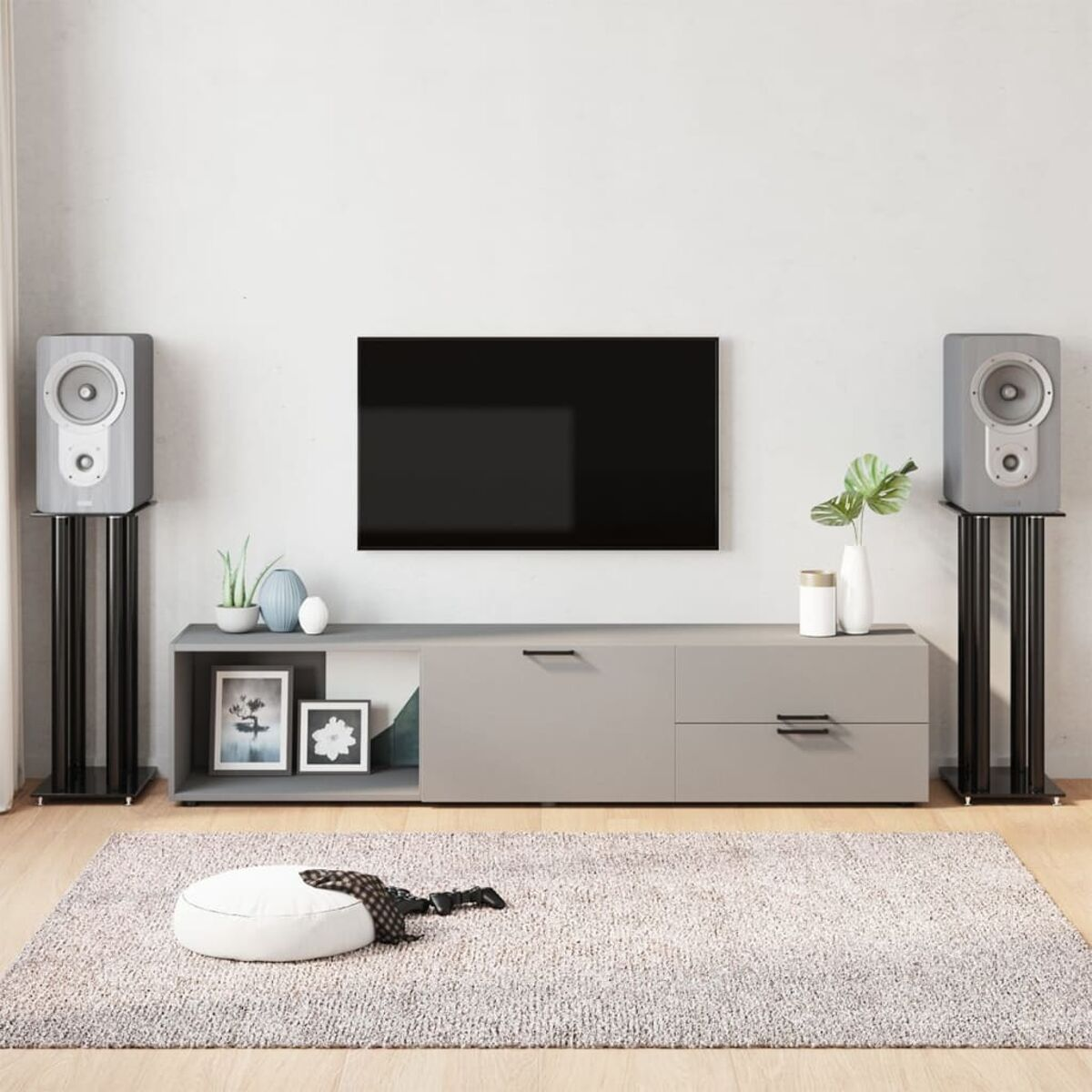 Wohnzimmer mit Fernseher, Lautsprechern und einem modernen grauen Schrank auf einem Teppich.