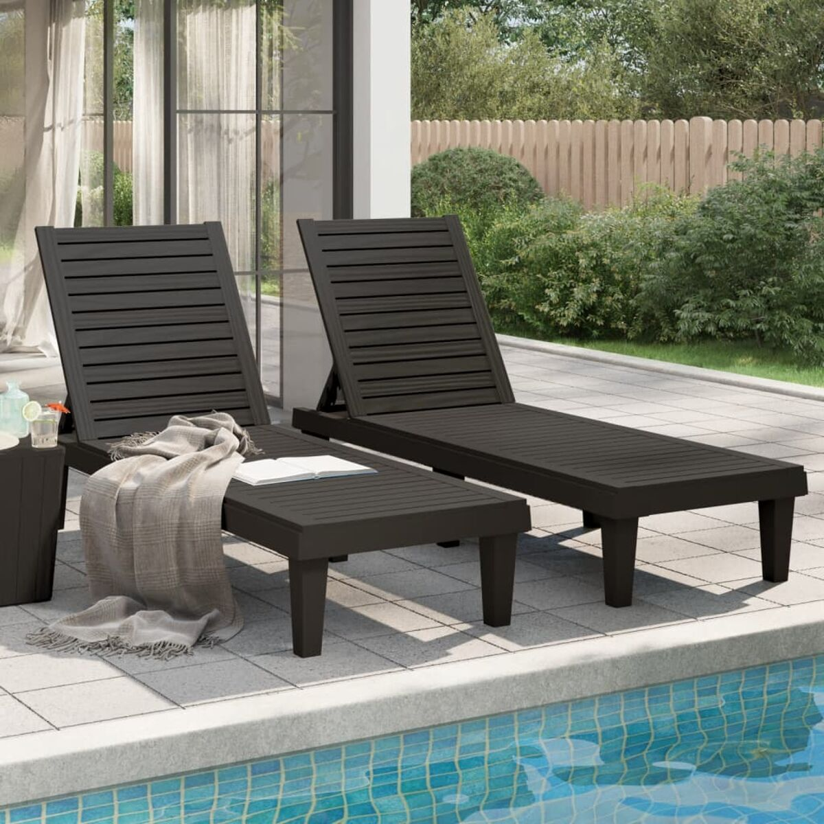 Zwei braune Outdoor-Liegestühle an einem Pool.