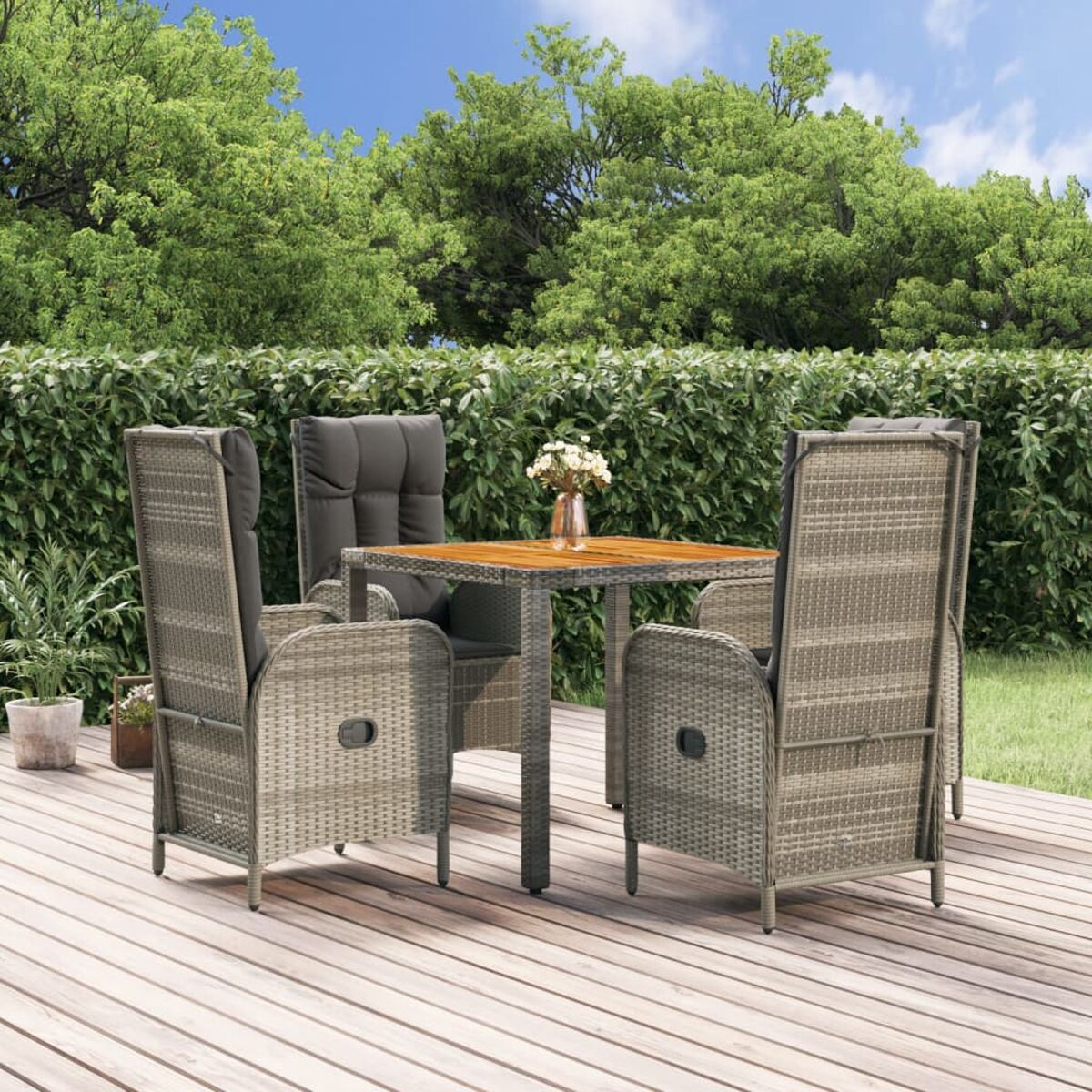 Terrassenmöbel-Set mit Tisch, Stühlen und Kissen. Grüne Bäume und Terrasse im Hintergrund.