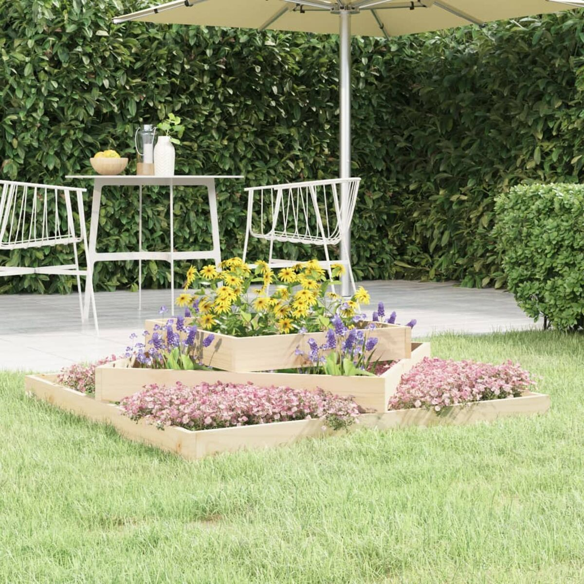 Gestuftes Blumenbeet aus Holz mit verschiedenen bunten Blumen. Grüner Rasen und weißer Tisch im Hintergrund.