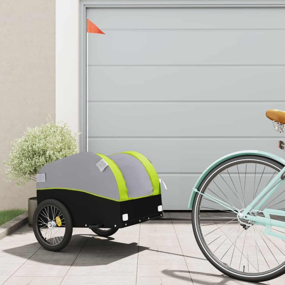 Fahrrad zieht grauen und schwarzen Anhänger mit grünen Akzenten. Garagentor im Hintergrund.