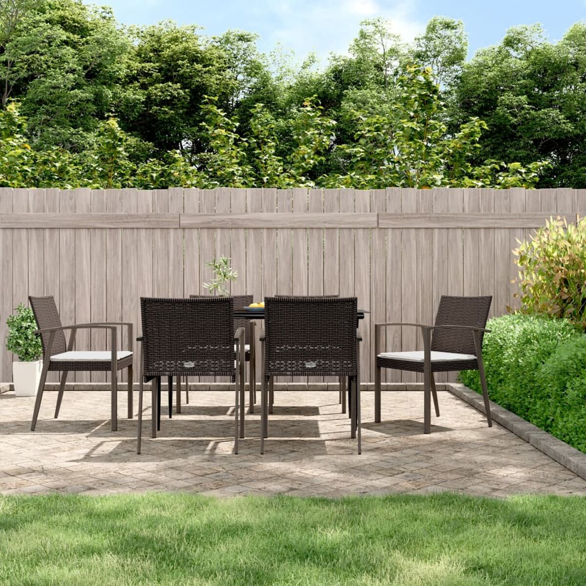 Essgruppe für draußen auf einer Ziegelterrasse. Enthält Tisch, Stühle und Grün im Hintergrund.