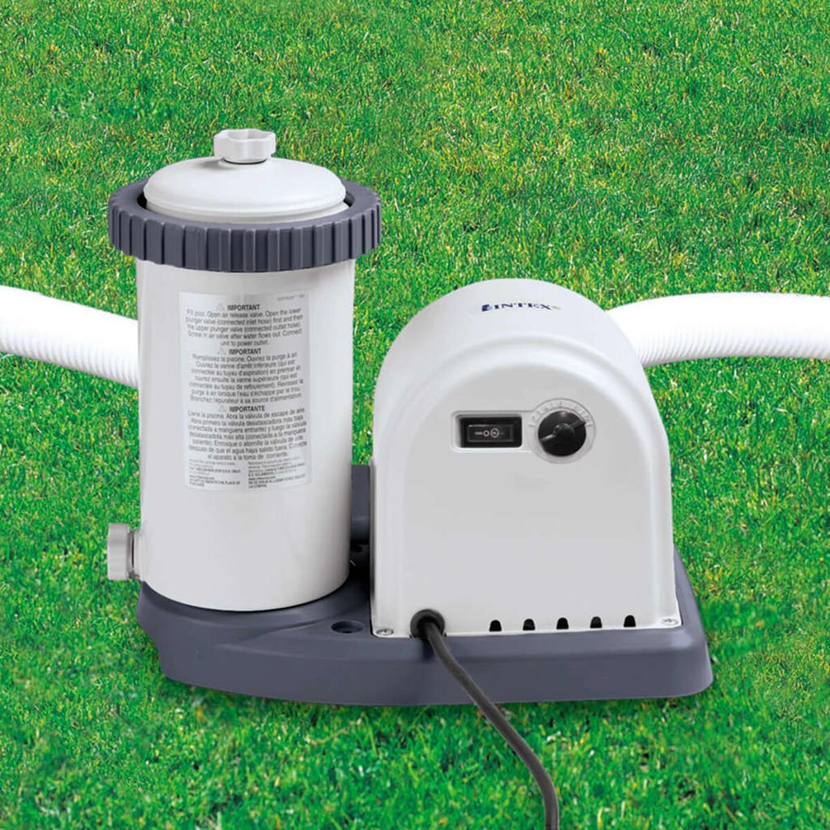 Weißer und grauer Poolfilter und Pumpe auf grünem Gras. Weiße Schläuche befestigt.