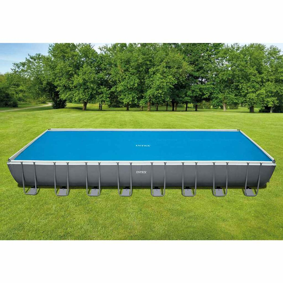 Rechteckiger Aufstellpool mit blauer Abdeckung. Grünes Gras und Bäume im Hintergrund.