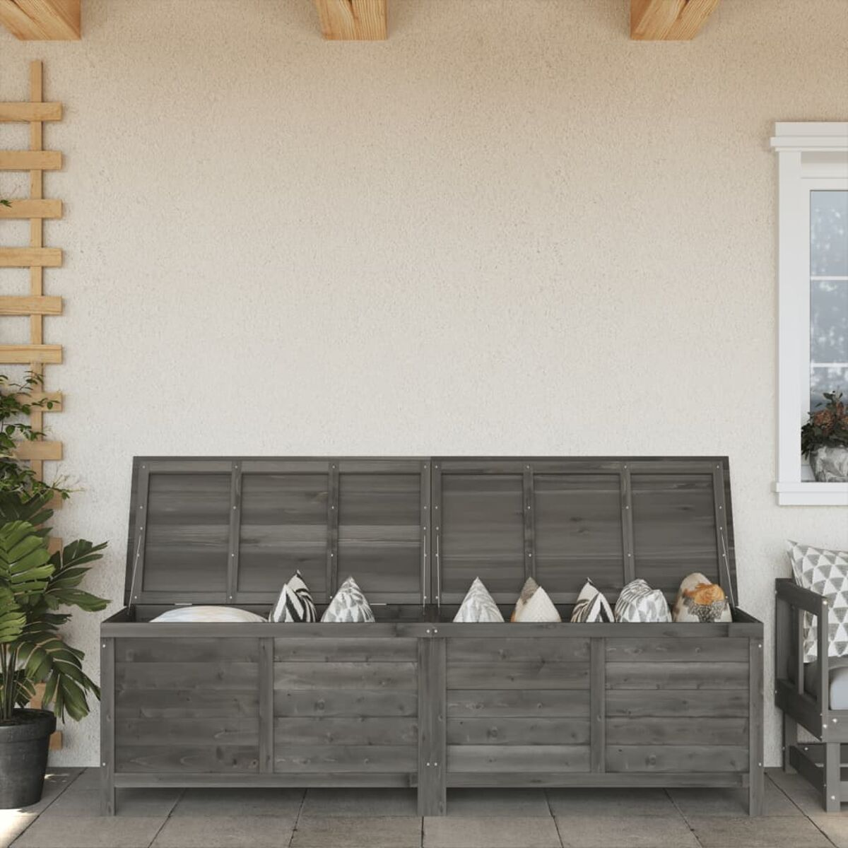 Holz-Außenaufbewahrungstruhe mit offenem Deckel.  Innen Kissen. Hintergrund Wand und Pflanze.