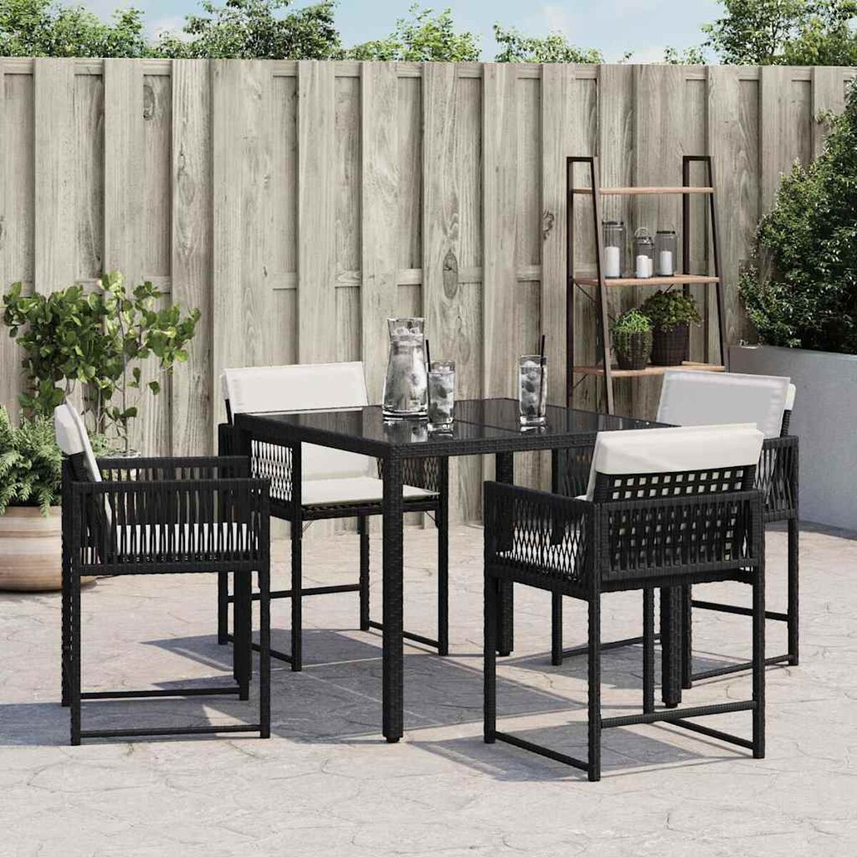 Set da pranzo per esterni. Mobili in vimini neri. Tavolo quadrato. Cuscini bianchi. Patio.