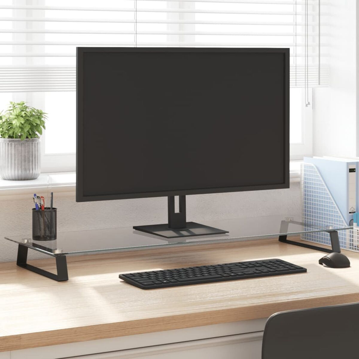 Computermonitor auf einem Glasständer. Tastatur und Schreibtischzubehör sichtbar.