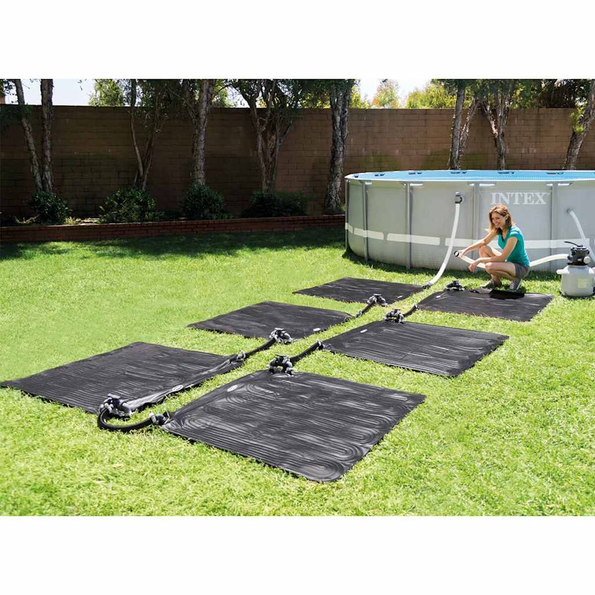 Frau am Pool mit Solarpanelen auf Gras, Schläuche verbunden.