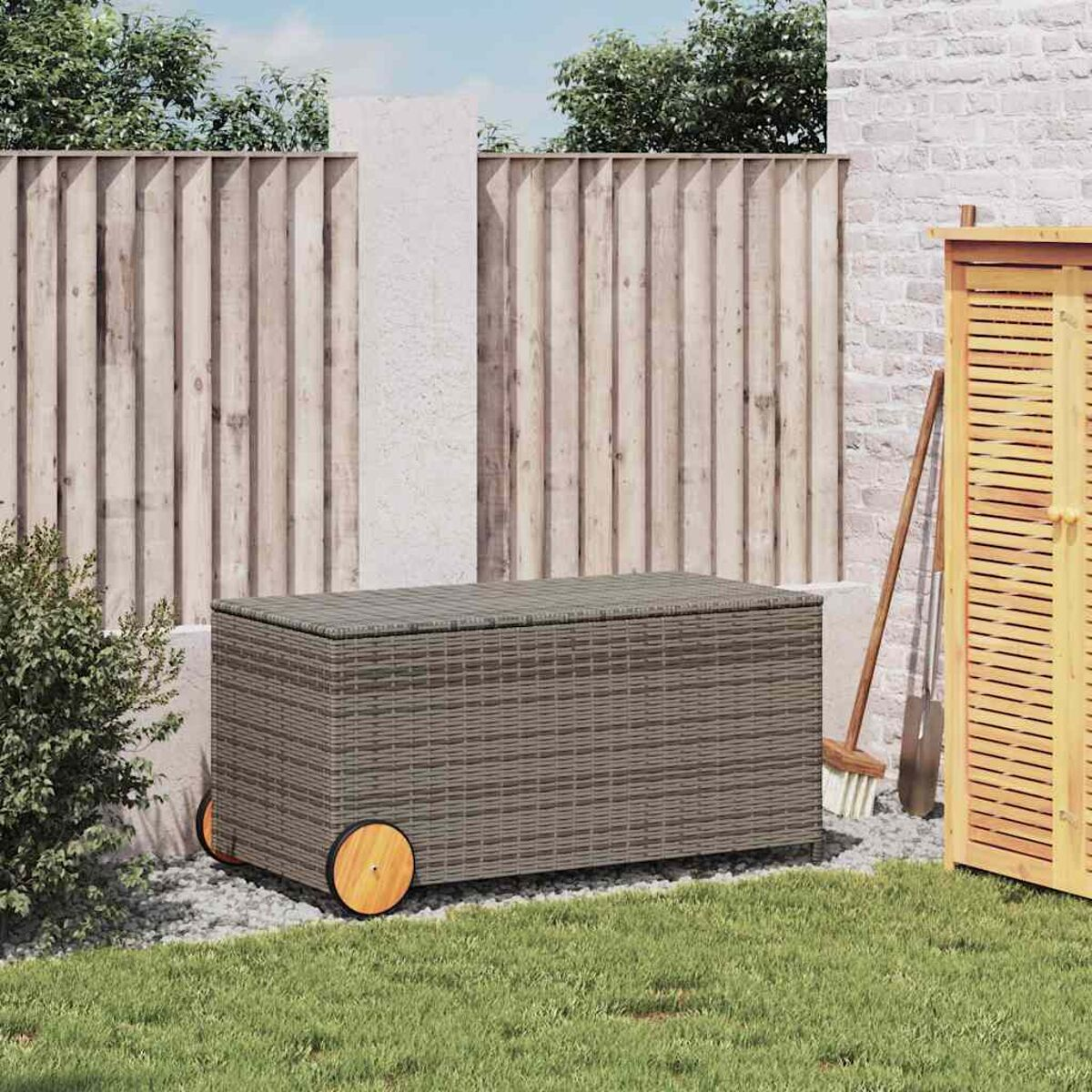 Eine graue gewebte Aufbewahrungsbox auf Rädern in einer Gartenszene. Es gibt einen Zaun, Pflanzen und einen Schuppen.
