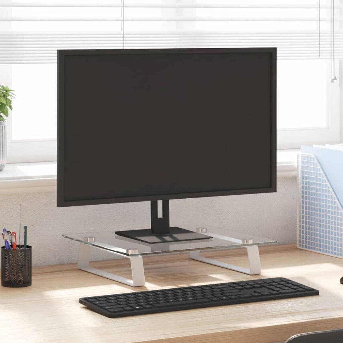Ein Computermonitor auf einem Glasständer, mit Tastatur, Stiften und einem Fenster.