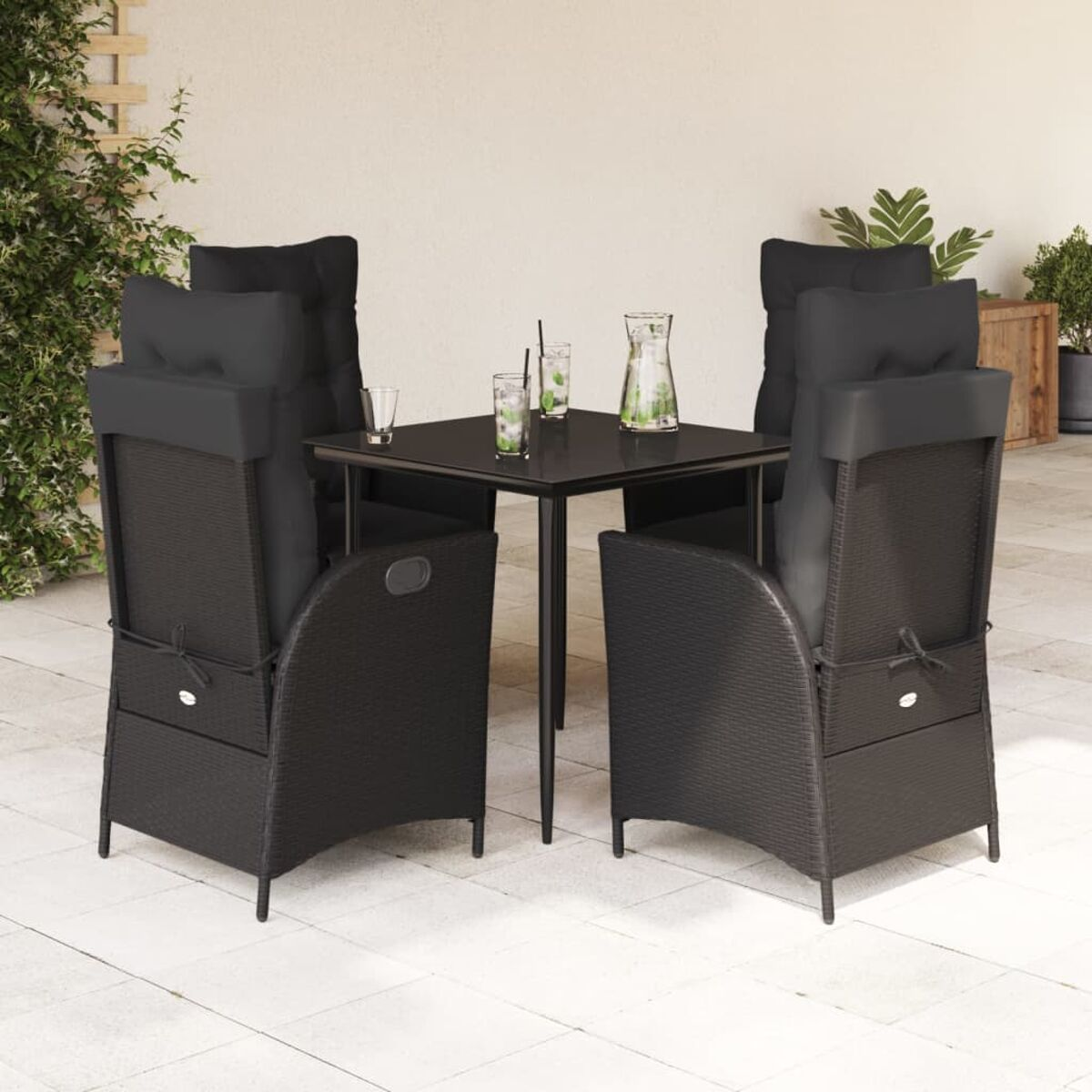 Set da pranzo in vimini nero da esterno con quattro sedie, un tavolo e bicchieri. Cuscini neri.