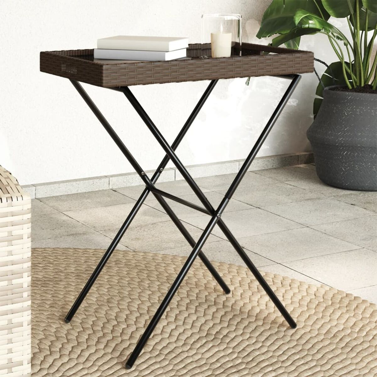 Ein brauner Tabletttisch aus Weide auf einem schwarzen Metallgestell auf einer gewebten Matte.