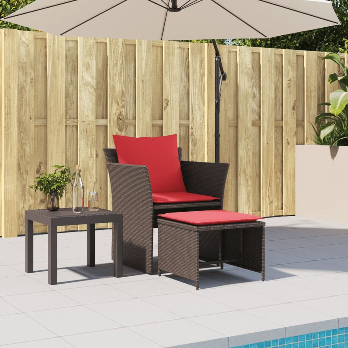 Outdoor-Set mit einem braunen Korbsessel, rotem Kissen, Beistelltisch und Sonnenschirm. Am Pool.