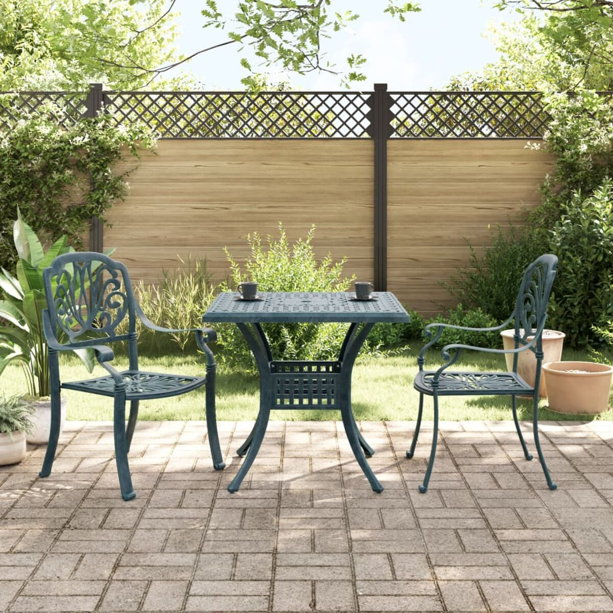 Gartentisch und Stühle auf einer Backsteinterrasse, mit Garten im Hintergrund.