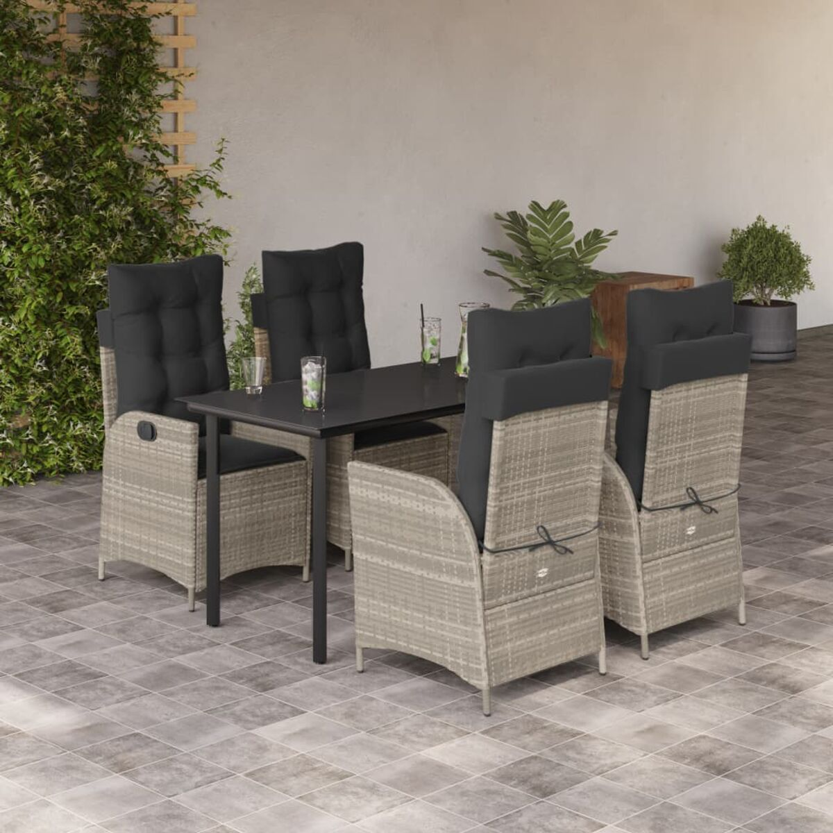 Set da pranzo all'aperto con tavolo nero, sedie in rattan con cuscini, su patio piastrellato.
