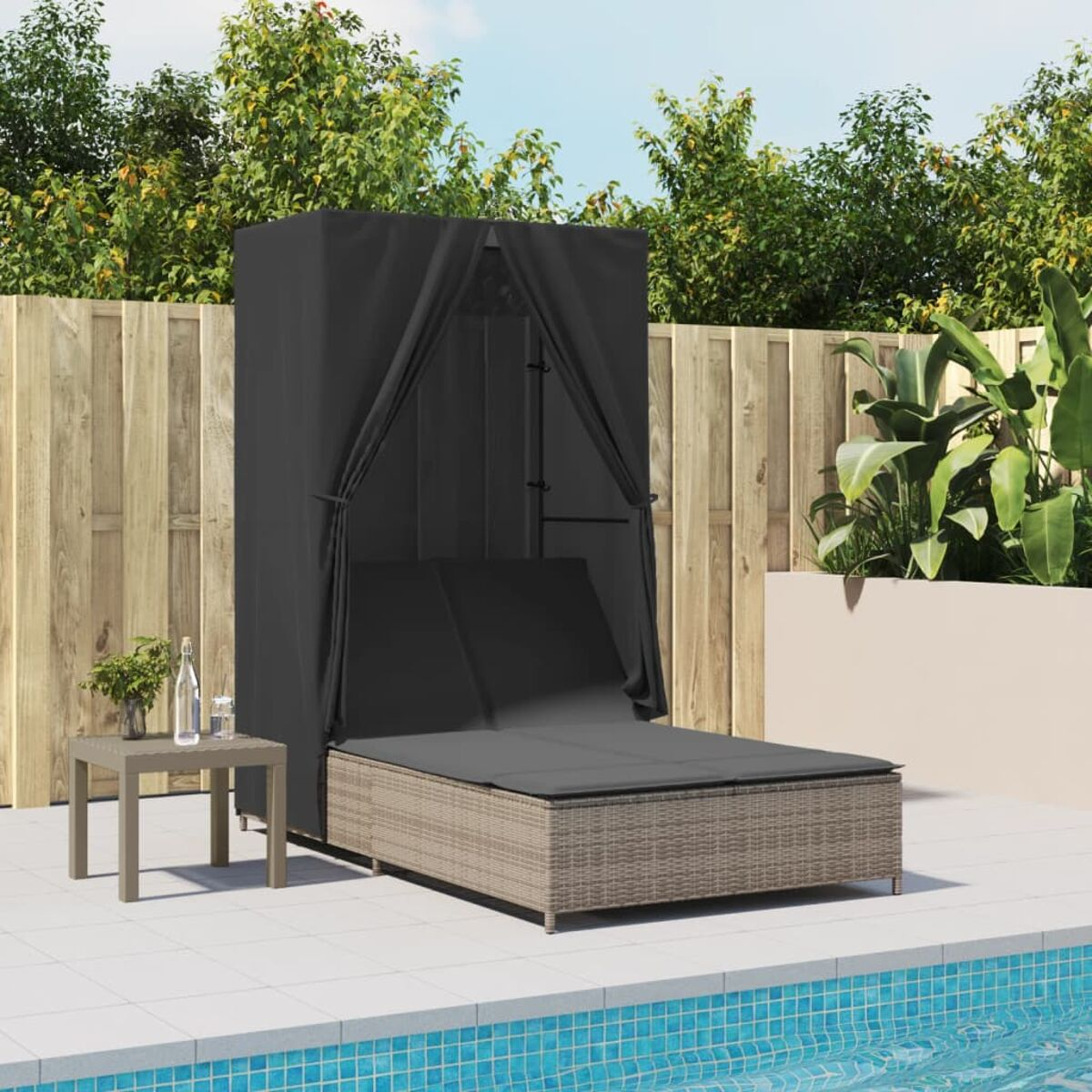 Un salotto a bordo piscina con un lettino e un tavolino. Un baldacchino nero offre ombra.