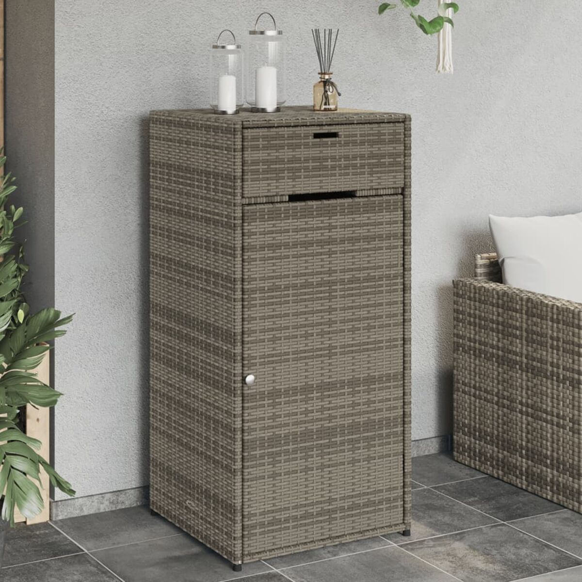 Ein gewebter Outdoor-Schrank mit Schublade und Tür, mit Deko oben drauf.