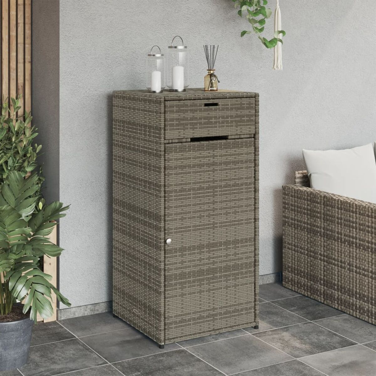 Ein Rattan-Schrank mit Schublade und Tür. Hintergrund: eine Wand und ein Sofa.