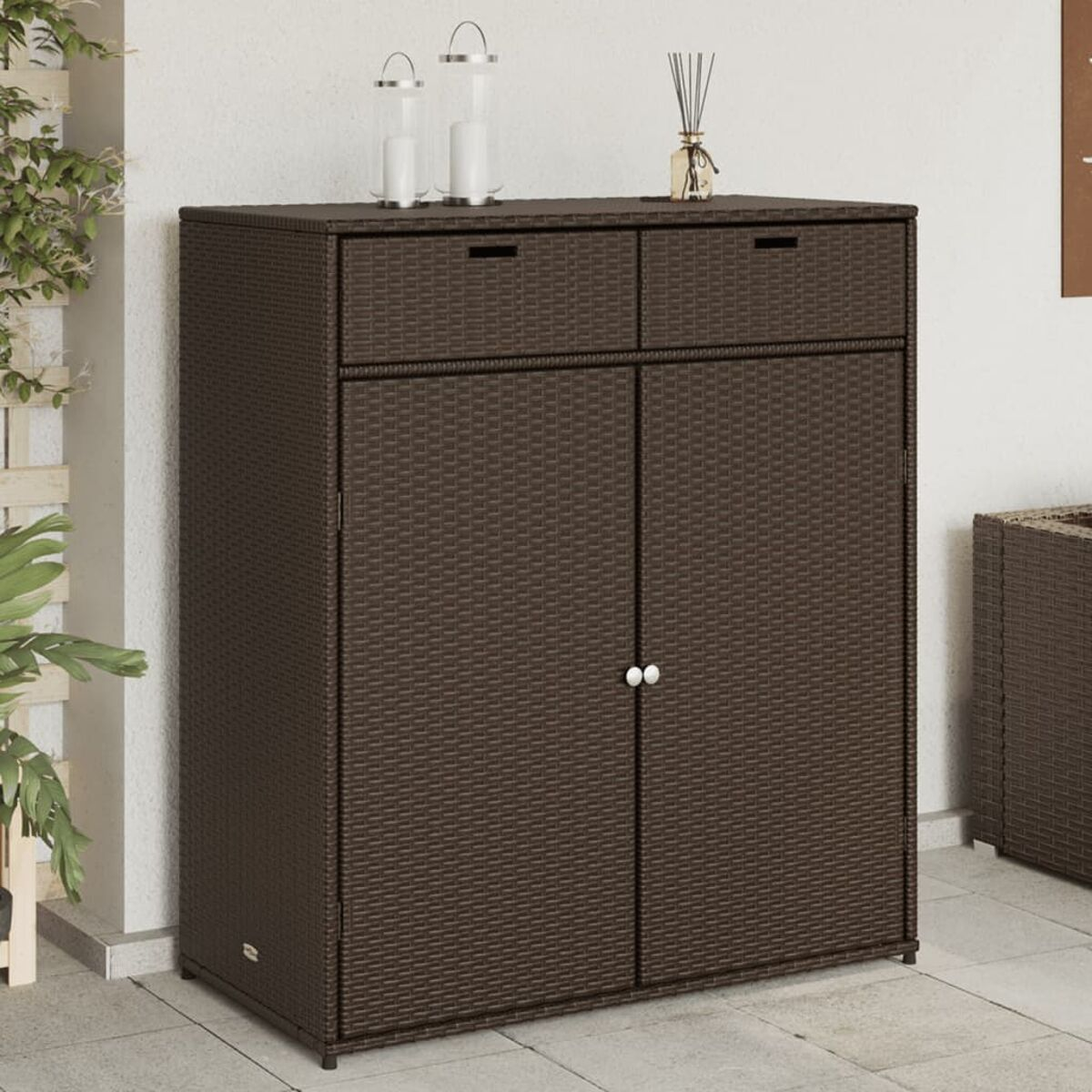 Ein brauner Weidenschrank mit zwei Schubladen und zwei Türen, mit Deko oben.