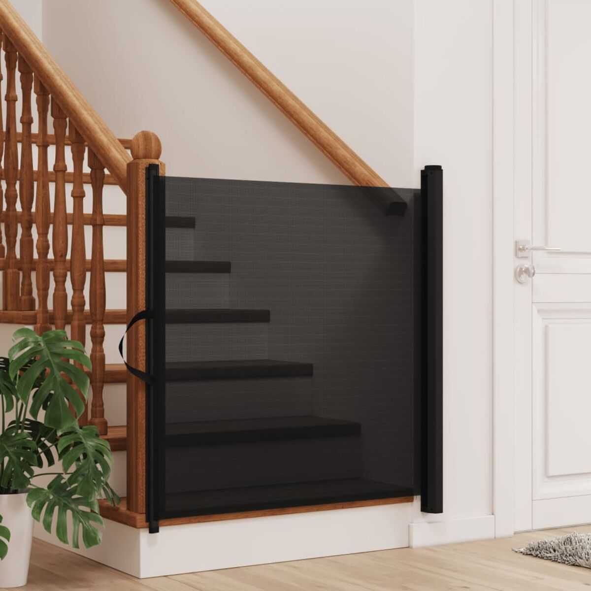 Ein schwarzes, einziehbares Sicherheitsgitter ist oben auf einer Treppe installiert. Eine Pflanze davor.