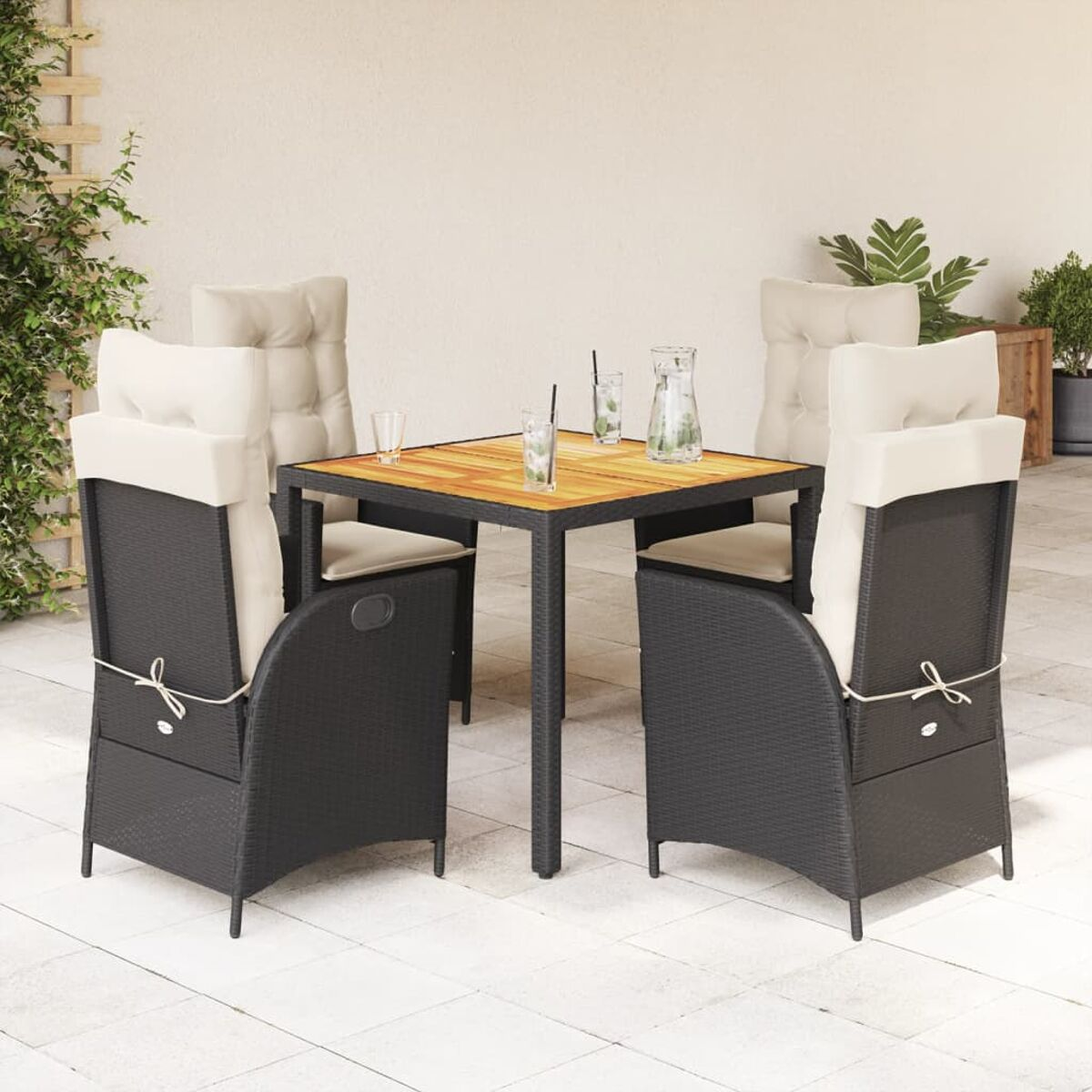 Essgruppe für den Außenbereich. Ein quadratischer Holztisch mit Stühlen. Schwarze Korbstühle und weiße Kissen.