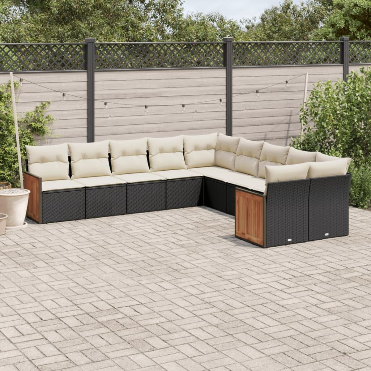 Schwarzes Outdoor-Ecksofa mit cremefarbenen Kissen. Das Set steht auf einer gefliesten Terrasse.
