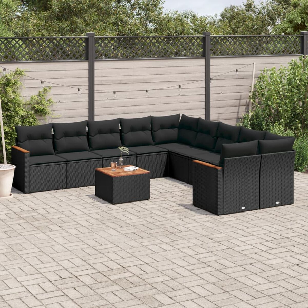 Outdoor-Rattan-Sofagarnitur, schwarz mit schwarzen Kissen und einem Holztisch.