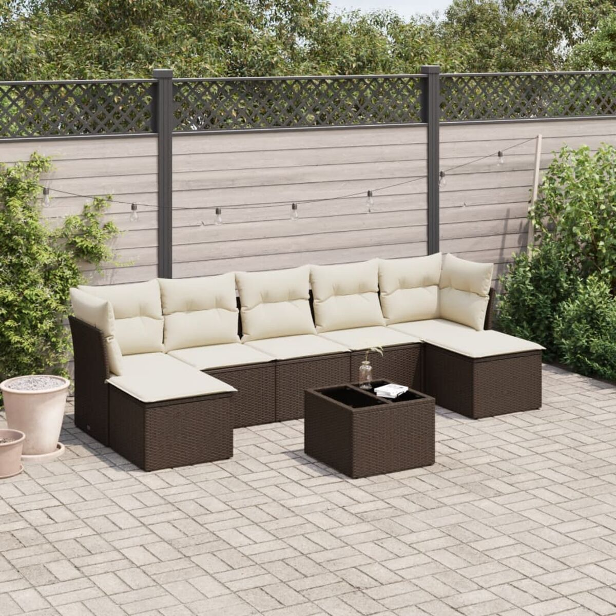Divano angolare in rattan marrone con cuscini beige su un patio. Un tavolino da caffè davanti.