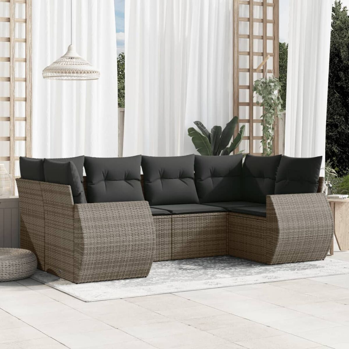 Outdoor-Ecksofa aus Rattan mit grauen Kissen. Die Szene spielt auf einer Terrasse.