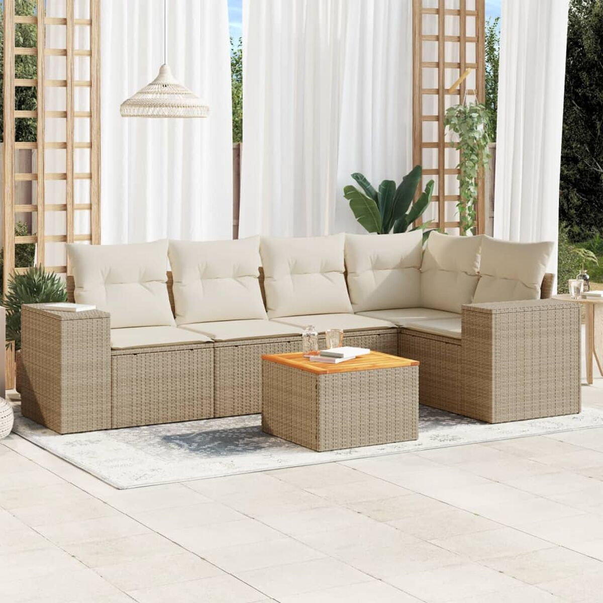 Szene im Freien mit einem Korbmöbel-Set, einem Holztisch und einer Pendelleuchte. Weiße Vorhänge und Pflanzen sind sichtbar.