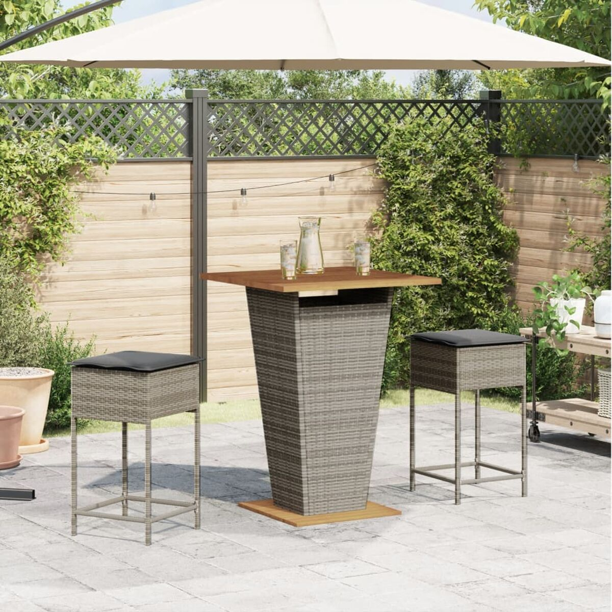 Tavolo alto con sgabelli, ombrellone sullo sfondo, ambiente patio esterno.