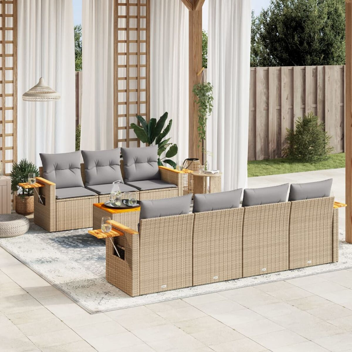Beige Outdoor-Sofa-Set aus Korbgeflecht mit grauen Kissen. Weiße Vorhänge, Pflanzen und Holzstruktur.