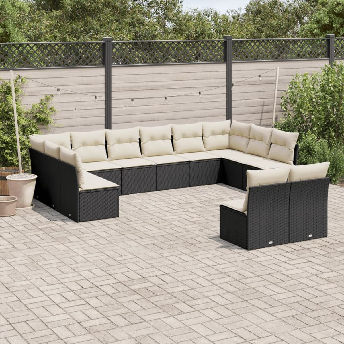 Schwarzes Outdoor-Ecksofa-Set aus Korbgeflecht, cremefarbene Kissen, auf einer Terrasse.