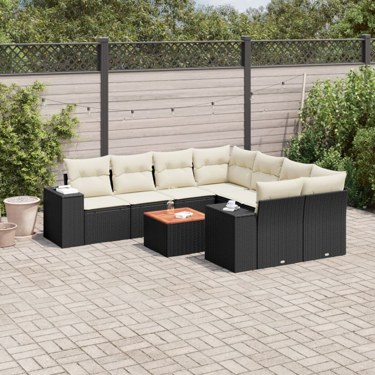 Schwarzes Outdoor-Ecksofa mit weißen Kissen und einem Tisch auf einer Ziegelterrasse.